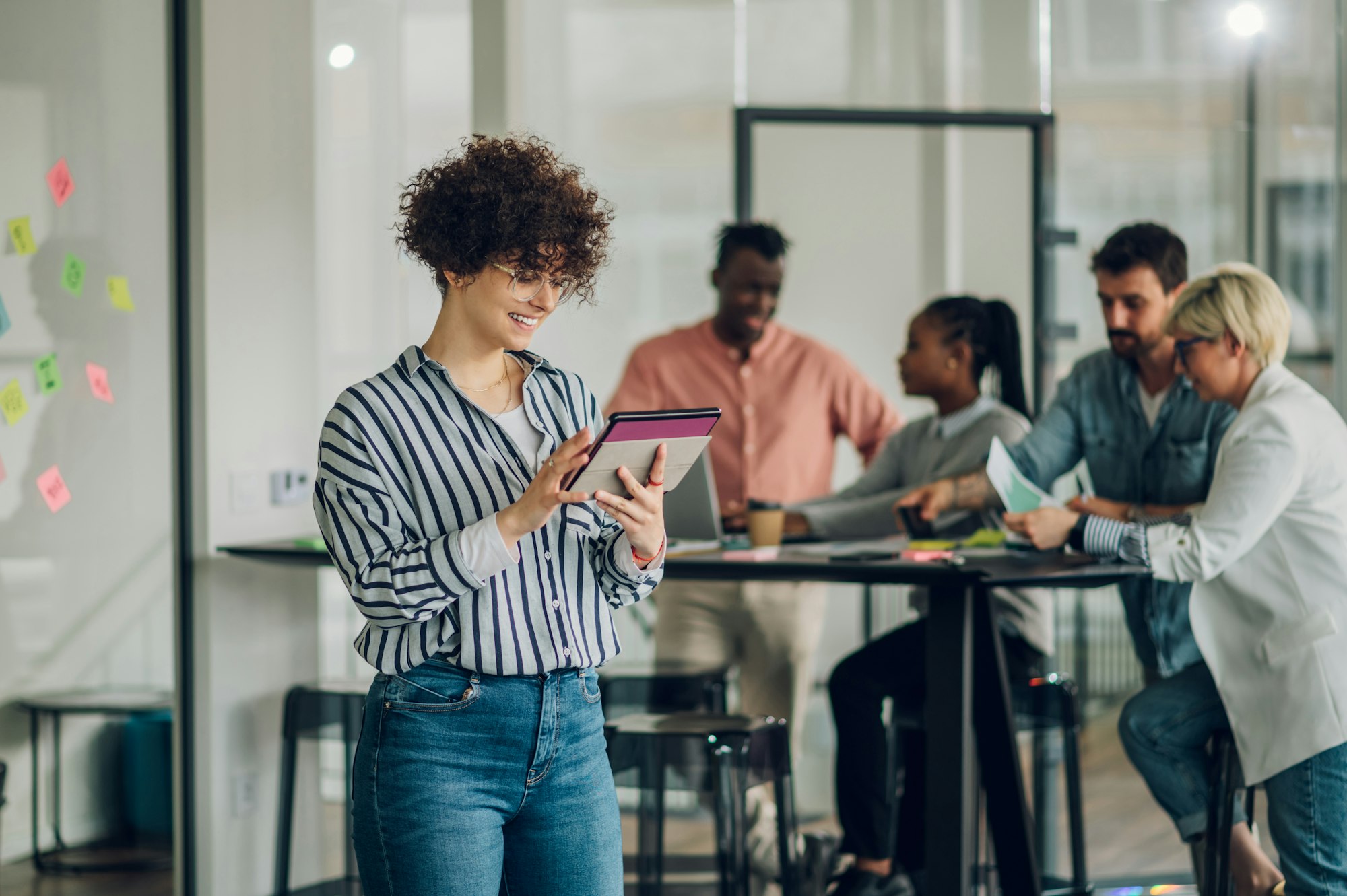 Portrait of a business woman standing in a office with colleagues in the back